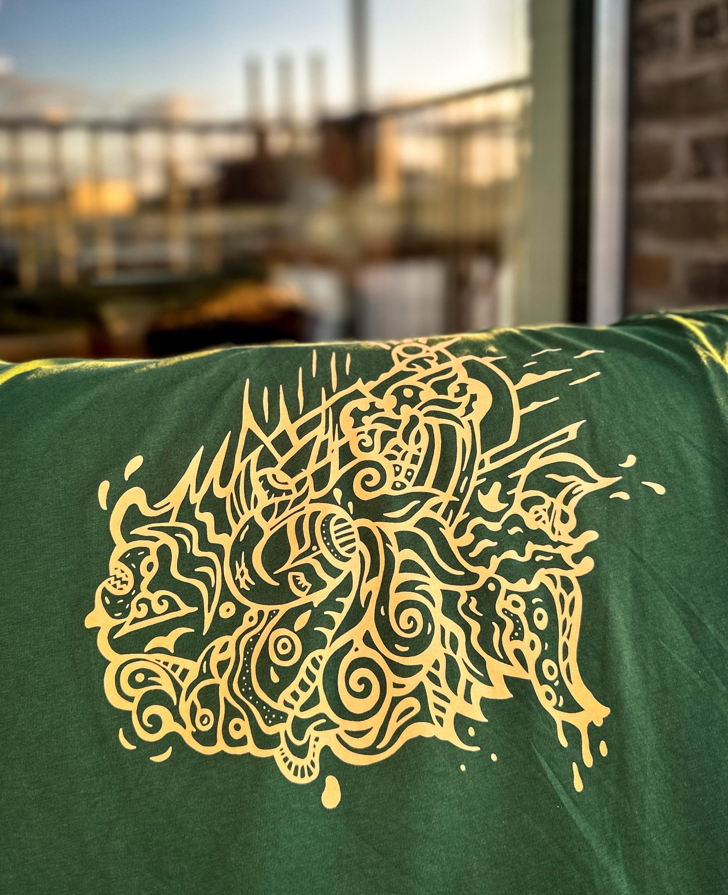 Green t-shirt with orange seawave design on a blurred background from SOAL Studio in Copenhagen and NOKUKO