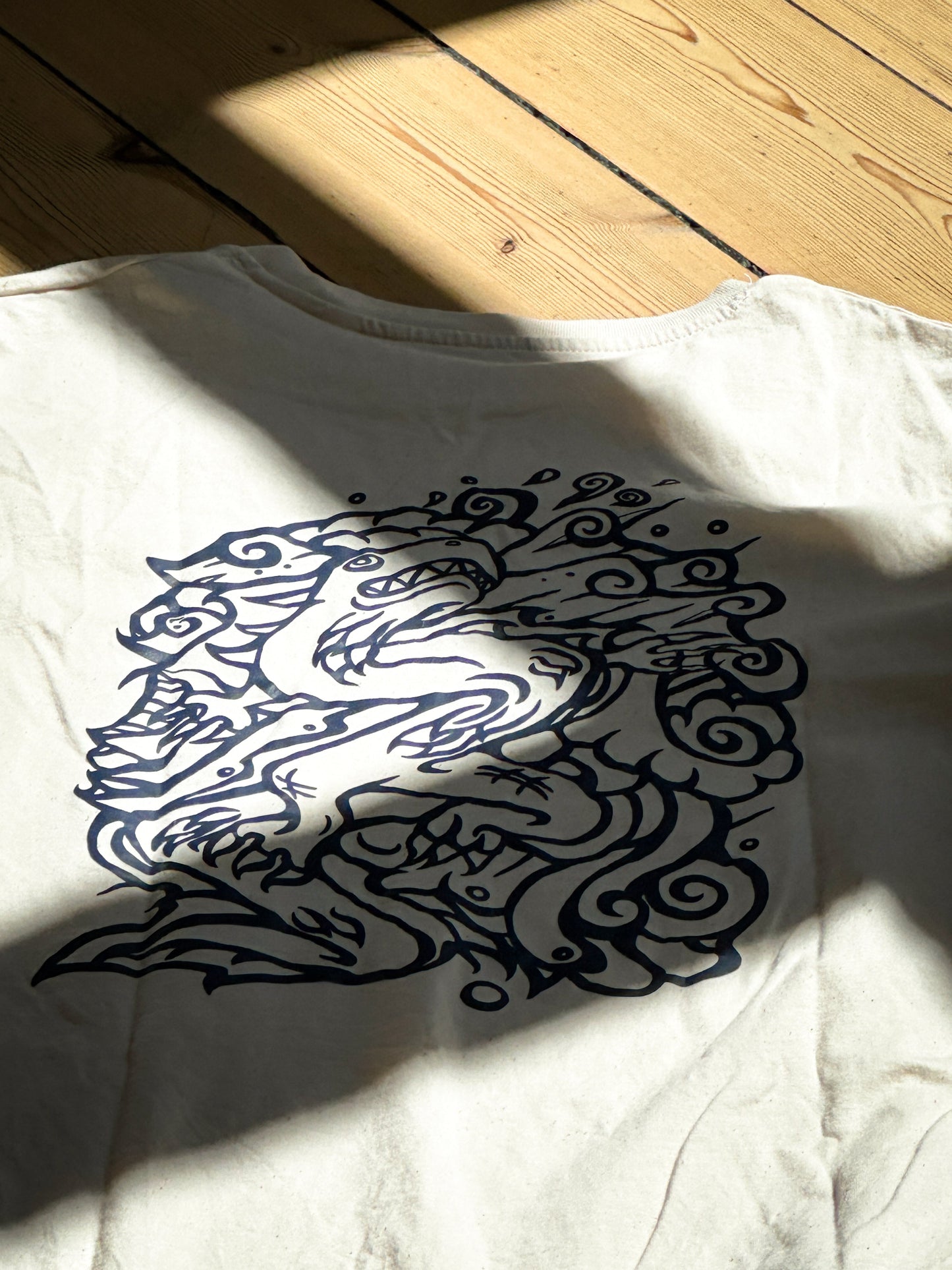 Beige SOAL Studio t-shirt with a navydragon design on a wooden floor