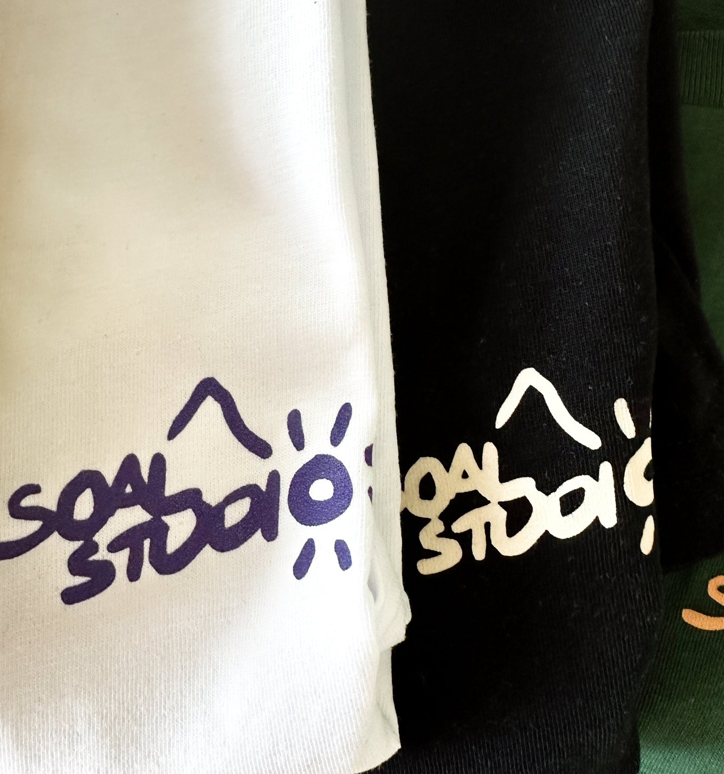 Two clothing items with 'SOAL STUDIO' branding in different colors. Here's white, black and green.